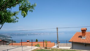 Une propriété clôturée offrant une vue dégagée sur un lac et sur le paysage urbain au loin.