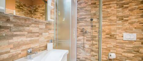 Ein modernes Badezimmer mit einer gläsernen Duschkabine, einer weißen Badewanne und einer Toilette.