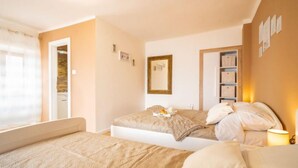 Une chambre avec deux lits, une table de chevet avec une lampe, un miroir et un mur décoré de tableaux encadrés.