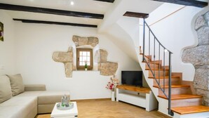 Un salon moderne avec un mur d’accent en pierre, un escalier en bois et un canapé blanc.