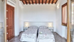 Ein Zimmer mit zwei Betten, Holzbalken an der Decke, weißen Wänden und einer Tür.