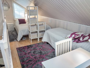 Un dormitorio compacto con una cama litera, un tocador blanco, una mesita pequeña y una alfombra estampada.