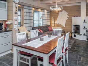 Eine moderne Küche mit Essbereich, Holzwänden, Kamin und einer Kristallleuchter.