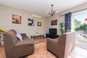 A living room with two brown sofas, a glass coffee table, a flat-screen TV, and artwork on the walls.