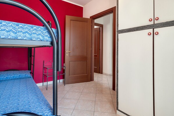 Una habitación con literas, un armario, una puerta y una silla.