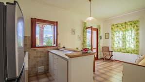 Eine Küche mit Kühlschrank, Spüle und Essbereich mit einem Stuhl.