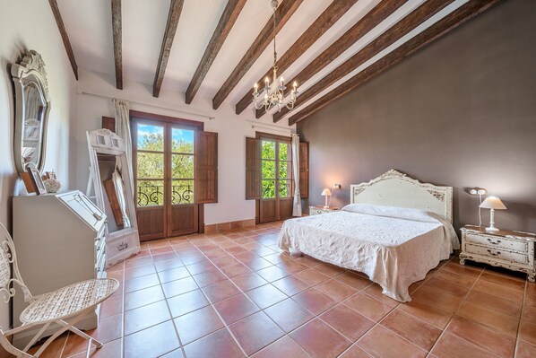 A bedroom with a bed, a dresser, a chair, a mirror, and a chandelier. - Stunning Villa Son French with Mountain View, Wi-Fi (algaida)