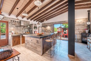 A modern kitchen with exposed beams, a central island with stools, and rustic decor. - Stunning Villa Son French with Mountain View, Wi-Fi (algaida)