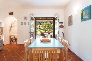 Comedor con mesa y sillas, vistas al jardín y puerta que da al exterior.