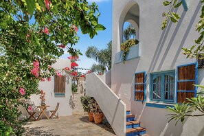 A courtyard with a stone floor, a wooden table and chairs, and potted plants. - Charming Apartment with Pool, Terrace, Air Conditioning and Wi-Fi (Conil)