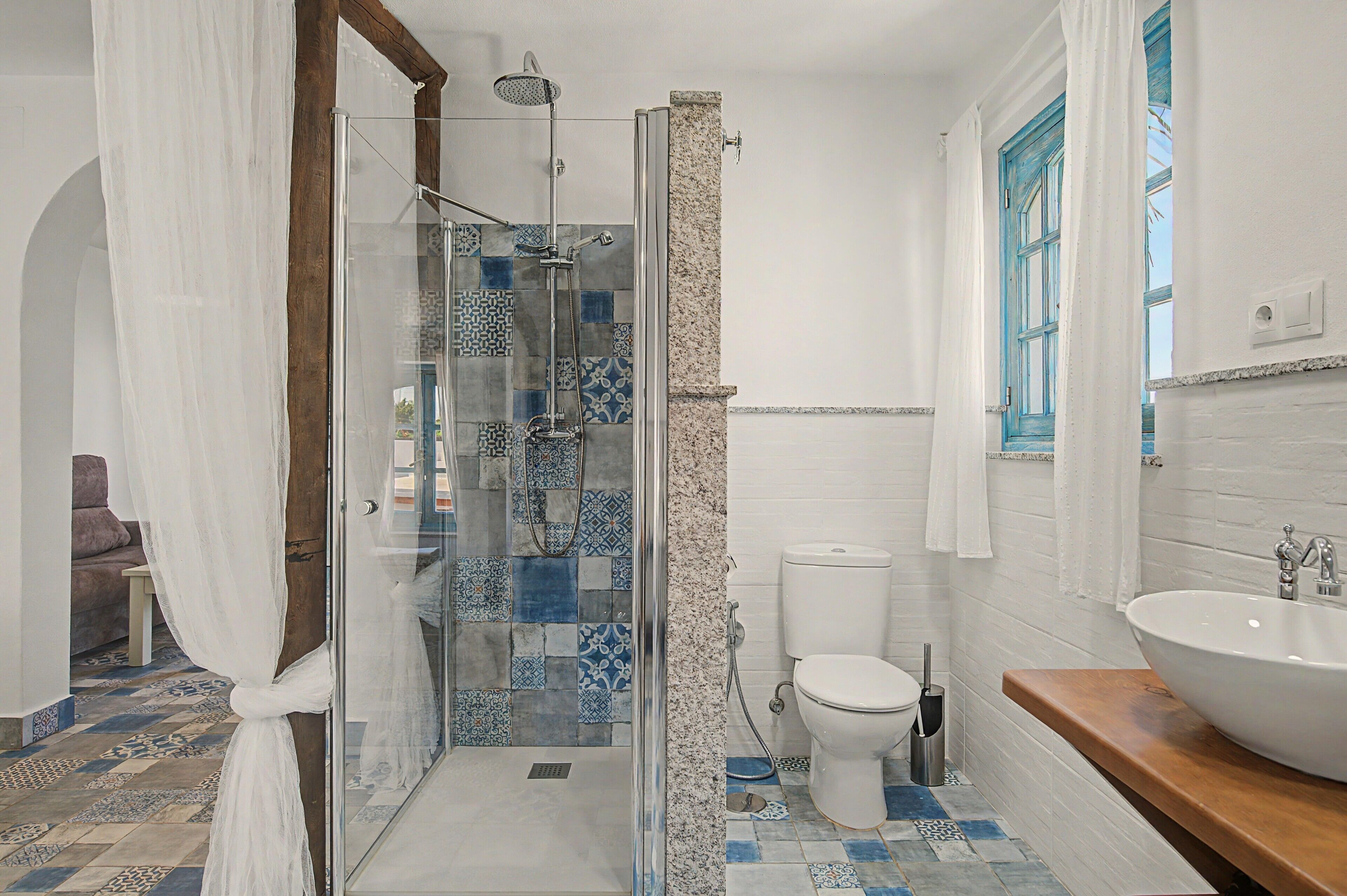 A bathroom with a glass shower enclosure, a white toilet, and a large sink.