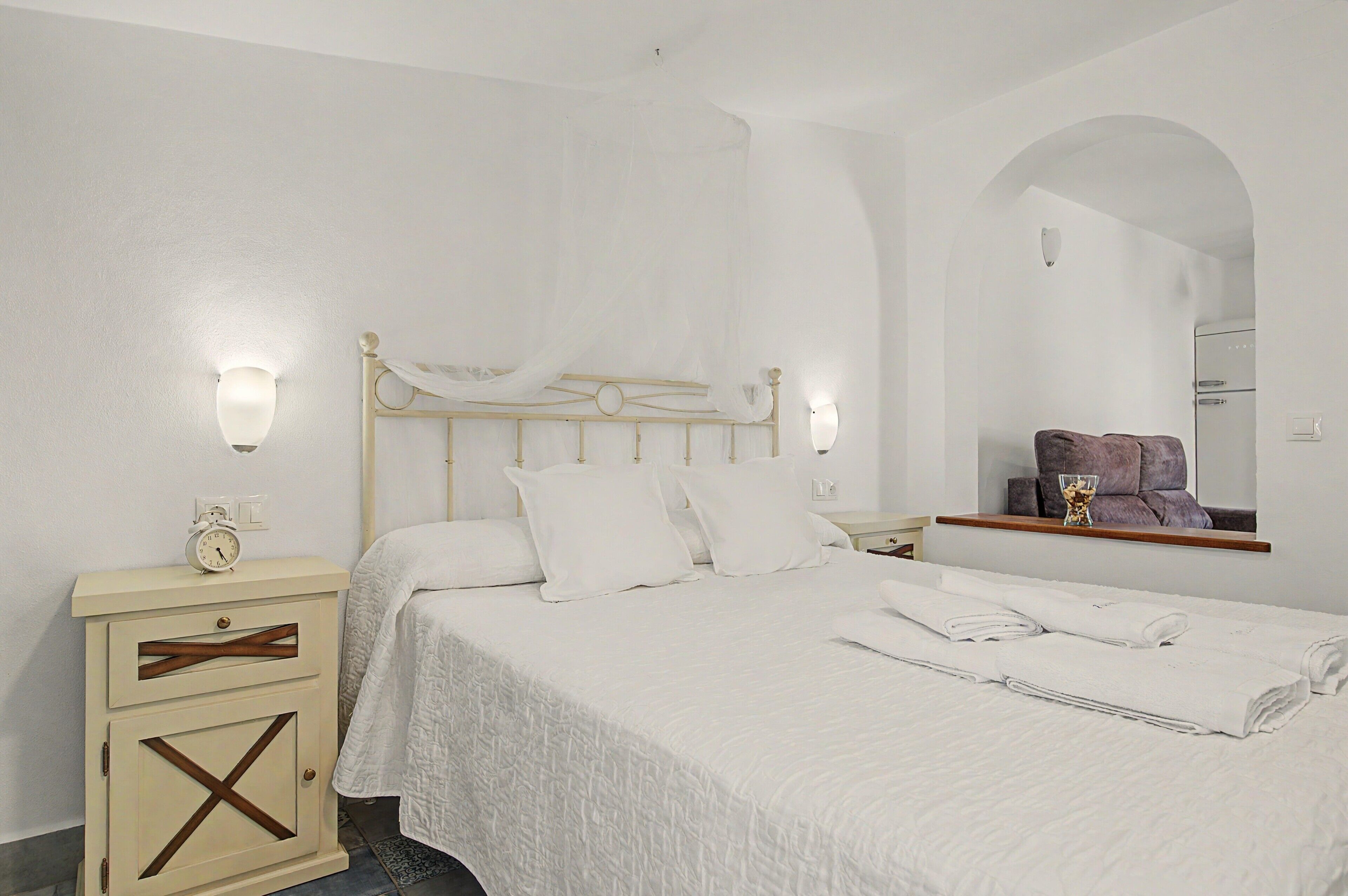 Une chambre à coucher avec un lit, des tables de chevet, un miroir et une armoire.
