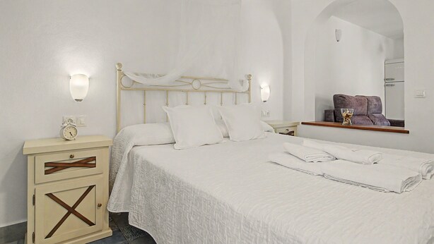 Ein Schlafzimmer mit einem Bett, Nachttischen, einem Spiegel und einem Kleiderschrank.