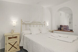 A bedroom with a bed, bedside tables, a mirror, and a wardrobe.