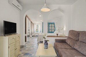 A modern living room with a television, sofa, and a table with a vase. - Charming Apartment with Pool, Terrace, Air Conditioning and Wi-Fi (Conil)