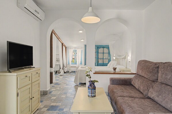 A modern living room with a television, sofa, and a table with a vase.