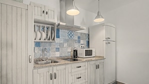 A kitchen with white cabinetry, a microwave, a sink, and pendant lighting. - Charming Apartment with Pool, Terrace, Air Conditioning and Wi-Fi (Conil)