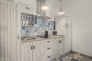 A kitchen with white cabinetry, a microwave, a sink, and pendant lighting.