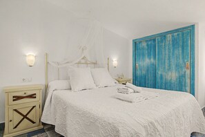 A bed with a canopy, a bedside table, a nightstand, and a blue door. - Charming Apartment with Pool, Terrace, Air Conditioning and Wi-Fi (Conil)