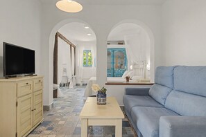 A living room with a television, sofa, and a table with a vase.