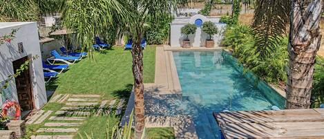 A swimming pool with a clear blue water, surrounded by a well-maintained lawn and various plants.