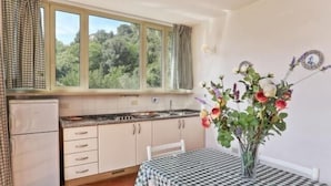Eine Küche mit Fenster, einem Tisch mit kariertem Tuch und einer Blumenvase.