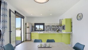 A modern kitchen with a dining area, featuring a large table, chairs, and a view through the sliding glass door. - Modern Holiday Home ''Casa Toria'' with Private Pool, Air Conditioning (Conil de la Fontera)