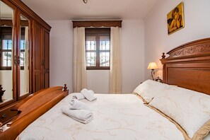 Een hotelkamer met een groot bed, een houten hoofdbord, een nachtkastje met een lamp, een kledingkast en een raam met gordijnen.