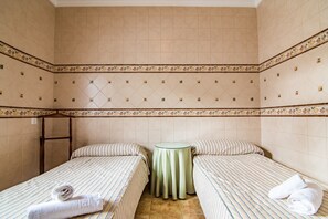 A room with two beds, a small table, and a ladder against the wall.
