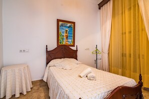 Une chambre à coucher avec un lit, une table de chevet, un tableau au mur et une fenêtre avec des rideaux.