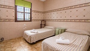 Habitación de hotel con dos camas, una ventana y una mesa verde.