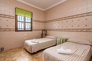 Een hotelkamer met twee bedden, een raam en een groene tafel.