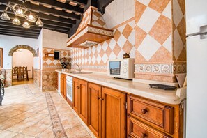 A kitchen with wooden cabinets, a microwave, and a tiled backsplash.