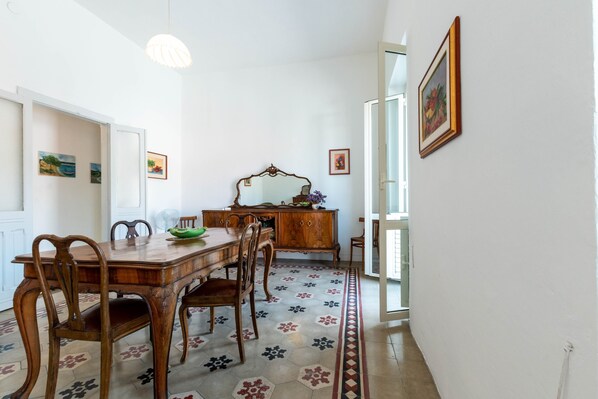 A dining area with a wooden table, chairs, a mirror, and a patterned rug.
