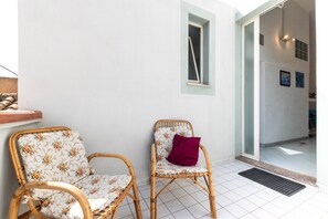 Two wicker chairs with floral upholstery, a small window, and a tiled floor.