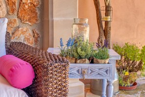 A cozy seating area with a woven chair, a small table with plants, and a candle lantern. - Fantastic Country House with Pool, Terraces, Garden, Air Conditioning & Wi-Fi (campos)