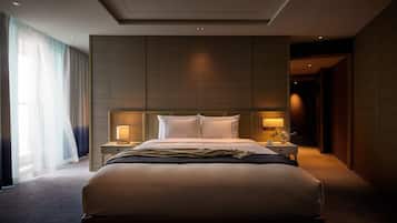 Una habitación de hotel moderna con una cama grande, dos mesitas de noche con lámparas, un ventanal con cortinas translúcidas y un panel de pared de madera.
