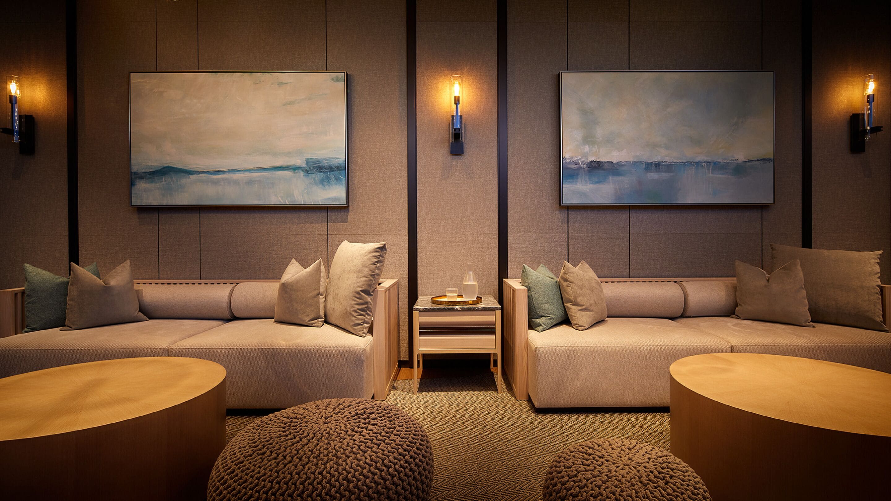 Une pièce moderne et bien éclairée, avec deux canapés placés face à face, une petite table sur laquelle se trouve un plateau, et un tapis à motifs.