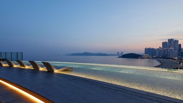 A waterfront promenade with modern seating and a view of the city skyline. - Signiel Busan (Busan)