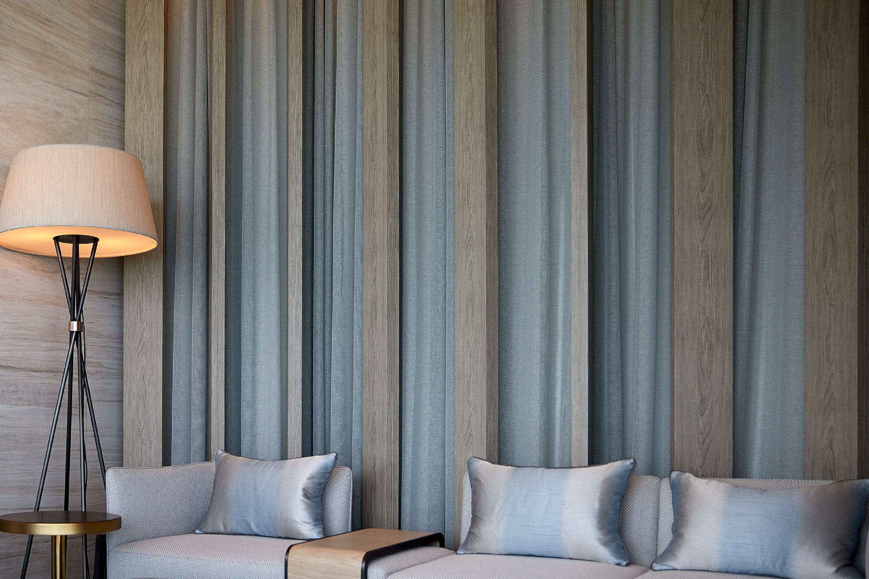 A modern living room with a sofa, a floor lamp, and vertical wooden panels.