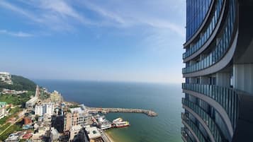 A high-rise building with a view of a coastal area, including a pier and a sandy beach.