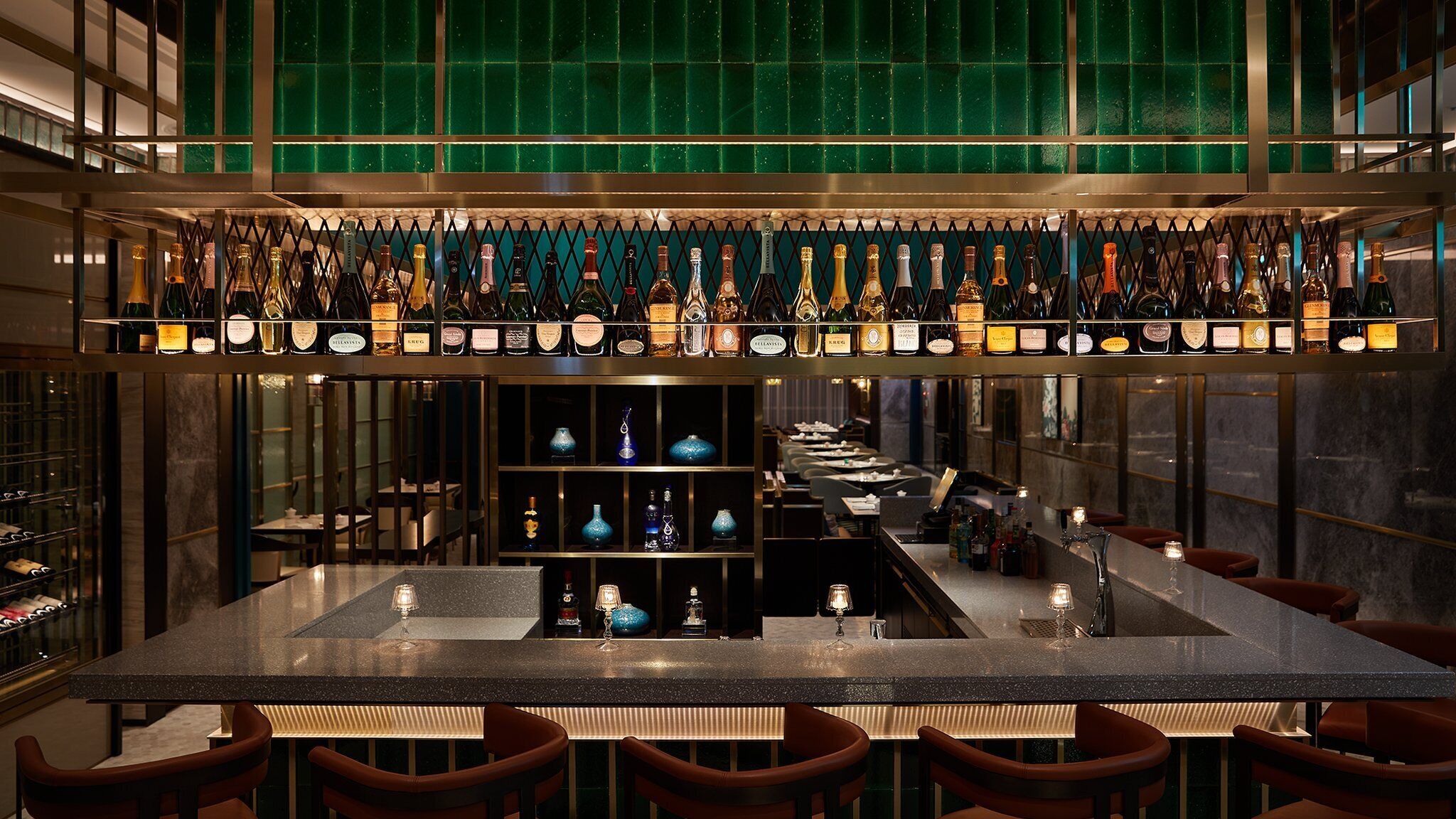 A bar area with multiple shelves of bottles, a central bar counter, and seating.
