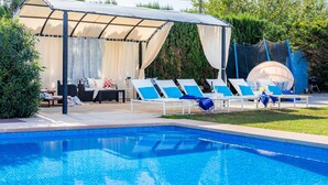 A pool with lounge chairs and a covered seating area.