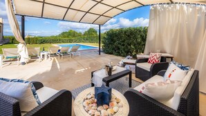 An outdoor patio with wicker furniture, a pool, and a view of the landscape.