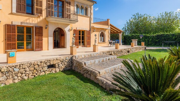 A two-story house with a stone foundation, wooden shutters, and a balcony.