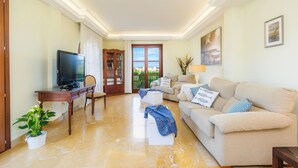 A living room with a TV, sofa, coffee table, and a potted plant.