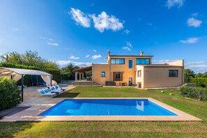 Une maison à deux étages avec une piscine, un patio couvert et une pelouse bien entretenue.