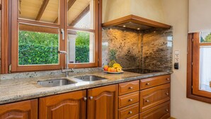 A kitchen with wooden cabinets, a granite countertop, a stainless steel sink, and a fruit bowl.