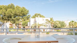 Ein Balkon mit Tisch und Stühlen, mit Blick auf ein Wohngebiet mit Gebäuden und Bäumen.