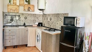 Eine kompakte Küche mit Waschmaschine, Mikrowelle und Gasherd.